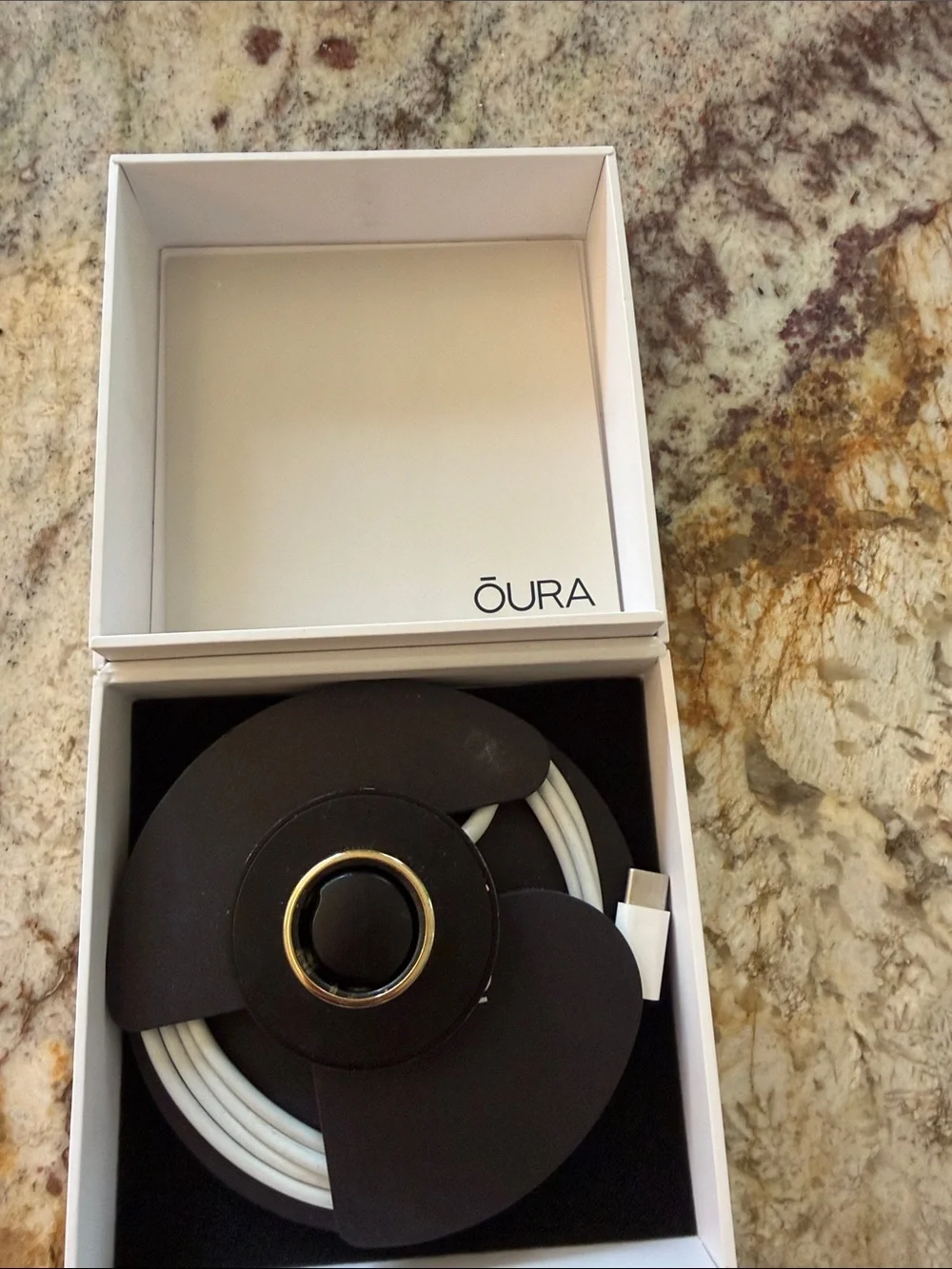 Oura Ring Model Gen 3. Charger for wellness ring with USB cable.